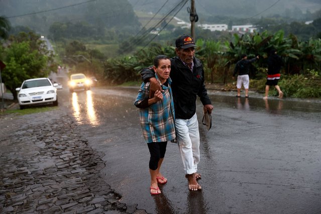People walk near the Taquari River during heavy rains in the city of Encantado, Rio Grande do Sul state, Brazil, on May 2, 2024. (Photo by Diego Vara/Reuters)