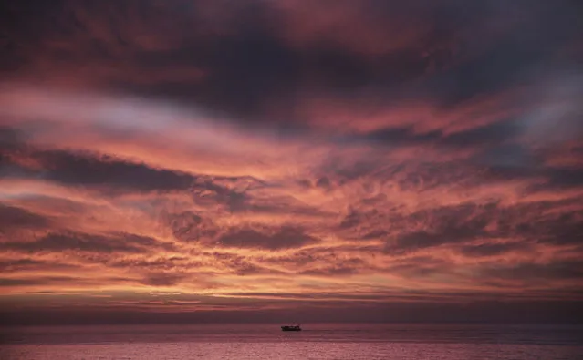 A Palestinian fishing boat sails as the sun sets on the coast off Gaza City, Sunday, March 18, 2018. (Photo by Khalil Hamra/AP Photo)