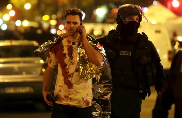 A French policeman assists a blood-covered victim near the Bataclan concert hall following attacks in Paris, France, November 14, 2015. (Photo by Philippe Wojazer/Reuters)