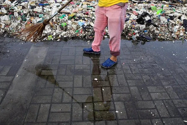 A government worker sweeps rubbish that was washed ashore by crashing waves due to strong winds of Super Typhoon Haima, local name Lawin, along the coastal areas in metro Manila, Philippines October 20, 2016. (Photo by Romeo Ranoco/Reuters)