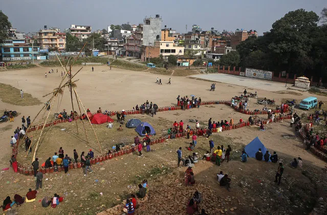 Nepalese people sit near empty cooking gas cylinders lines as they wait for fresh supply in Kathmandu, Nepal, Monday, November 16, 2015. Nepal's prime minister Khadga Prasad has asked neighboring India to lift an "undeclared blockade," saying the Himalayan nation is facing a severe fuel shortage and trouble obtaining medicine and food supplies blocked at the border. (Photo by Niranjan Shrestha/AP Photo)