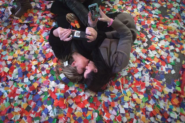 Lindsay Mann (L) and Anabella Mowbray kiss as they take photos of themselves laying in the confetti on 7th Avenue in Times Square on New Year's Eve in New York January 1, 2015. (Photo by Carlo Allegri/Reuters)