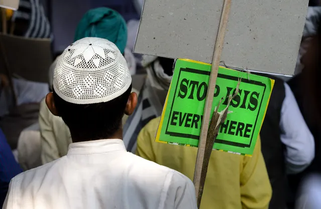 An Indian Muslim man holds a banner and listens to a speaker during a protest against ISIS, an Islamic State group, and Friday's Paris attacks, in New Delhi, India, Wednesday, November 18, 2015. Multiple attacks across Paris on Friday night have left more than one hundred dead and many more injured. (Photo by Manish Swarup/AP Photo)