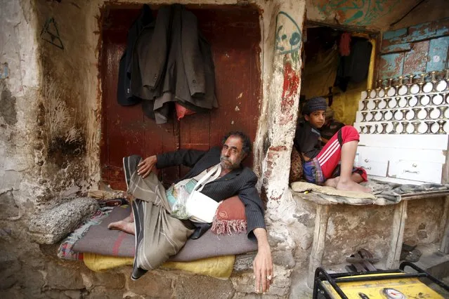 A man chews qat, a mild stimulant, as he sits next to a vendor selling daggers in the old quarter of Yemen's capital Sanaa November 27, 2015. (Photo by Khaled Abdullah/Reuters)