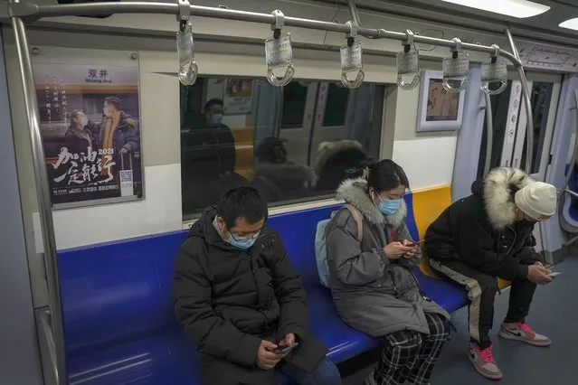 Commuters wearing face masks to help curb the spread of the coronavirus ride on a subway train near an advertisement carrying the words “Come on 2021, It will work” in Beijing, Tuesday, January 26, 2021. Countries must cooperate more closely in fighting the challenges of the pandemic and climate change and in supporting a sustainable global economic recovery, Chinese President Xi Jinping said on Monday in an address to the World Economic Forum. (Photo by Andy Wong/AP Photo)