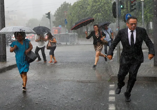 People cross a street during heavy rain in Frankfurt, Germany, June 7, 2018. (Photo by Kai Pfaffenbach/Reuters)