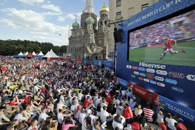 People watch on a huge screen the 2018 soccer World Cup match between Russia and Saudi Arabia at a fan zone in St.Petersburg, Russia, Thursday, June 14, 2018. (Photo by Dmitri Lovetsky/AP Photo)