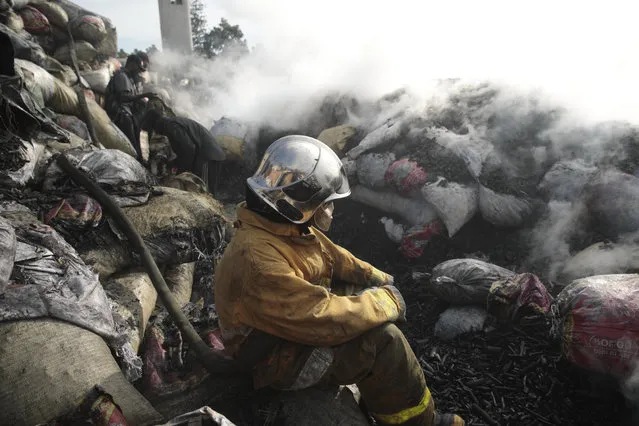 Firefighter stops working to put out a fire at the Shada Market after his fire truck ran out of water in the Petion-ville area of Port-au-Prince, Haiti, Thursday, May 4, 2023. The truck left the site to fill up with more water. (Photo by Joseph Odelyn/AP Photo)