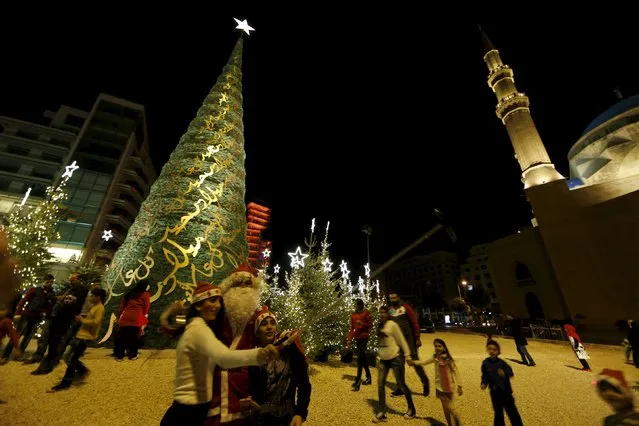 Children take a selfie with a man dressed as Santa Claus in front of a decorated Christmas tree in Beirut, Lebanon, December 12, 2015. (Photo by Jamal Saidi/Reuters)