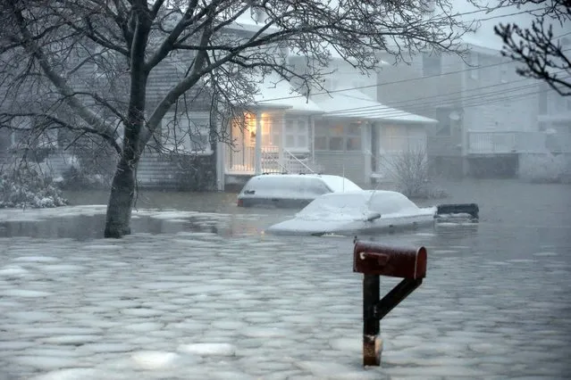 Water floods a street on the coast in Scituate, Mass., Tuesday, January 27, 2015. A storm packing blizzard conditions spun up the East Coast early Tuesday, pounding parts of coastal New Jersey northward through Maine with high winds and heavy snow. (Photo by Michael Dwyer/AP Photo)