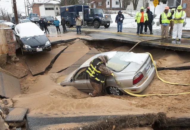 A tow truck operator placed a strap on the Honda Accord in the sinkhole in the 4200 block of Edmonston Road on January 27, 2015 in Bladensburg, MD. The sinkhole was caused by a 12-inch water-main break early Tuesday morning which also flooded a number of homes in the area. (Photo by Mark Gail/The Washington Post)