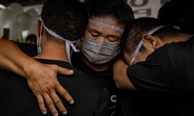Florentino Gregorio, husband of Sonya Gregorio and father of Frank Gregorio, hugs his remaining sons during the funeral of his wife and son on December 27, 2020 in Paniqui, Tarlac province, Philippines. Sonya Gregorio, 52, and her 25-year old son Frank Gregorio, were both shot in the head by an off-duty police officer before Christmas after a row over noise. The incident was captured in what is now a viral video that has provoked a wave of outrage directed at the government and a police force that many say acts with impunity. The shootings are the latest in a series of killings involving the Philippine National Police, which is currently the focus of an international investigation. A recent report by the International Criminal Court said there was reasonable basis to believe that crimes against humanity have been committed as part of President Rodrigo Duterte's bloody war on drugs in the Philippines. (Photo by Ezra Acayan/Getty Images)