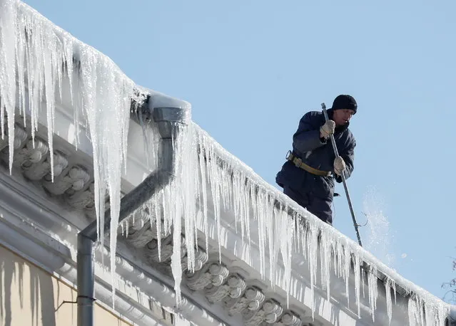 A municipal worker knocks down the icicles from a house roof in central Kyiv, Ukraine on February 19, 2021. (Photo by Gleb Garanich/Reuters)