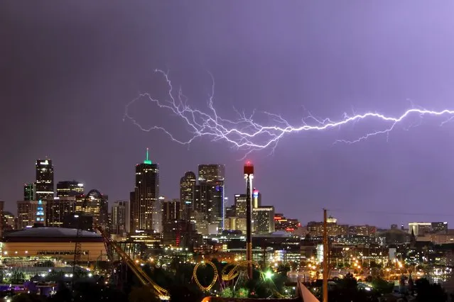 A huge blast of purple-tinged lightning streaks across a row of skyscrapers in Denver, Colorado. (Photo by Greg Thow/Barcroft Media)