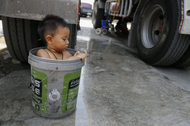 A boy bathes in a bucket next to his father's rice truck outside a rice mill in the central province of Chainat , Thailand December 16, 2015. (Photo by Jorge Silva/Reuters)