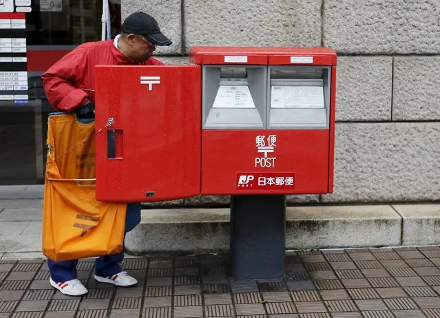 A worker of Japan Post Co collects postal items from a post box outside a post office in Tokyo, Japan, November 2, 2015. (Photo by Toru Hanai/Reuters)