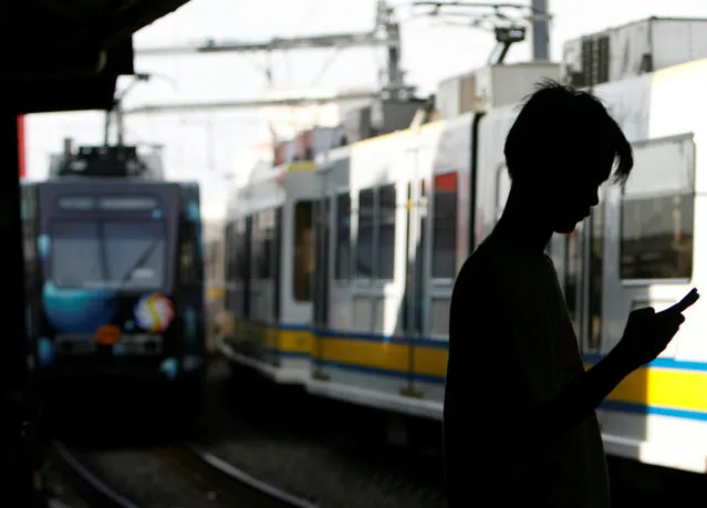 A commuter uses his mobile phone as a train arrives at a station in Pasay City, Metro Manila July 7, 2008. (Photo by Cheryl Ravelo/Reuters)