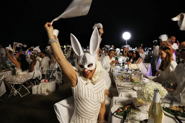 People wave their napkins at the start of dinner at the annual “Diner en Blanc” (Dinner in White) September 17, 2018 on Governor's Island in New York City. Diner en Blanc began in France nearly 30 years ago. Attendees all must wear white clothing and bring their own picnic food and white tables cloths. Over 6,000 people were alerted, only hours before, to the location of this year's gathering on Governor's Island which is only accessible by ferry. (Photo by Spencer Platt/Getty Images)