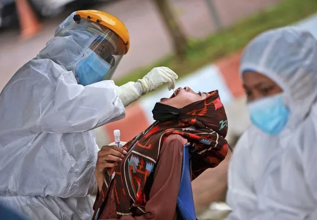 A medical worker collects nasal swab samples from a woman during a mass test for coronavirus at North Sumatra University (USU) Hospital in Medan, North Sumatra, Indonesia, Wednesday, June 2, 2021. (Photo by Binsar Bakkara/AP Photo)