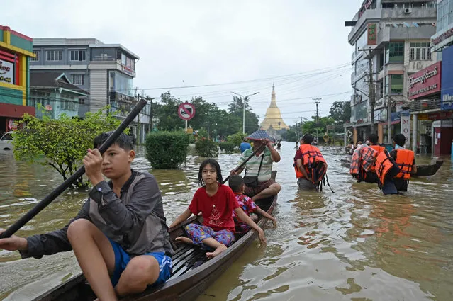 Local residents make their way through a flooded street after heavy rains in Bago township in Myanmar's Bago region on October 9, 2023. (Photo by Sai Aung Main/AFP Photo)