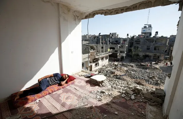 A Palestinian man sleeps in the ruins of his house that was destroyed in Israeli air strikes during Israeli-Palestinian fighting, in Gaza on June 9, 2021. (Photo by Mohammed Salem/Reuters)