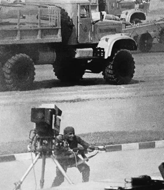 In this October 6, 1981 file photo, a man in Egyptian army uniform fires a Kalashnikov assault rifle at point blank range into presidential reviewing stand where President Anwar Sadat and several others were killed. In foreground, abandoned TV camera whose operator believed to be among the dead, in Cairo, Egypt. In background Soviet-made army truck on which the assassins arrived in military parade. (Photo by AP Photo)