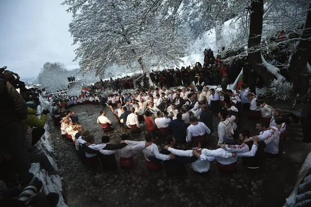 People perform a national dance called “Horo” while holding Bulgarian national flags during Epiphany Day celebrations in the icy waters of the river in the town of Kalofer, some 150 km from Sofia, Bulgaria, 06 January 2017. The Epiphany Day, also known as Three Kings Day, is a Christian feast day that celebrates the arrival of the Three Wise Men with their gifts for the infant Jesus, as well as the revelation of God taking human form as his son Jesus Christ. (Photo by Vassil Donev/EPA)