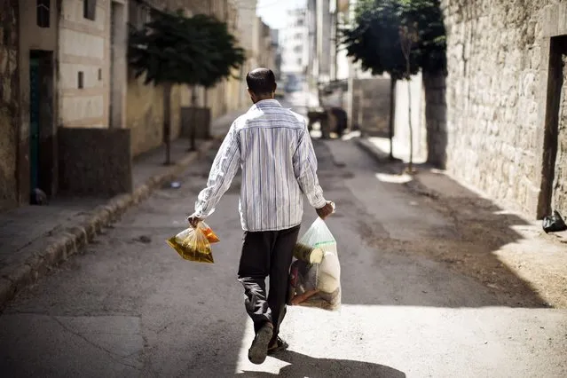 A Syrian man carries donated food supplies from an aid distribution centre in Aleppo on September 13, 2012. (Photo by Marco Longari/AFP Photo)