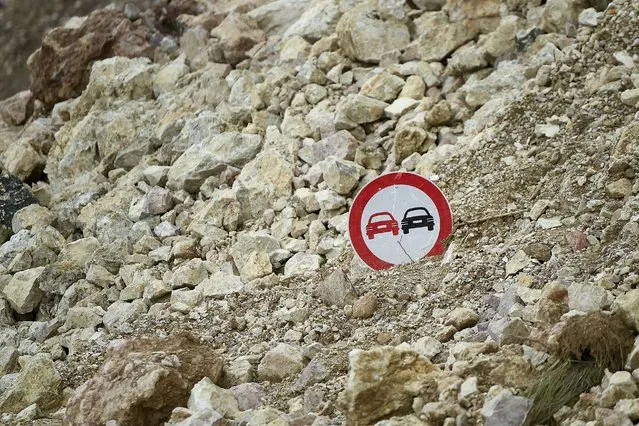 A traffic sign pokes out from the debris of a landslide triggered by Saturday's 7.2 magnitude earthquake, alongside a road in Rampe, Haiti, Wednesday, August 18, 2021. (Photo by Matias Delacroix/AP Photo)