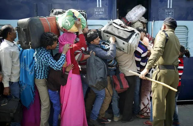 A policeman keeps order as people board a passenger train at a railway station in New Delhi, India, February 25, 2016. (Photo by Anindito Mukherjee/Reuters)