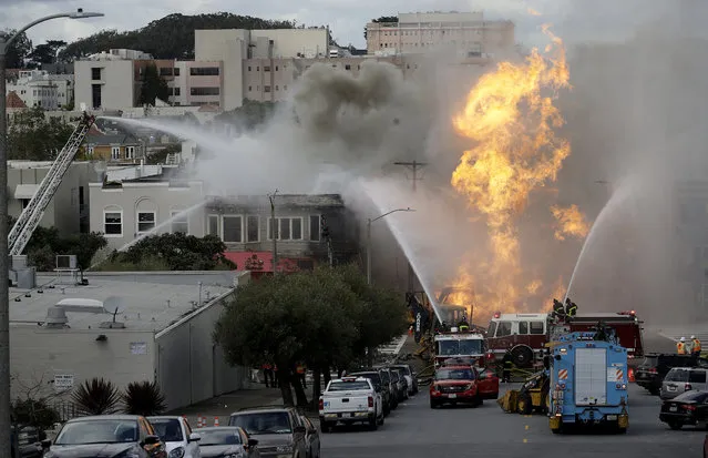 San Francisco firefighters battle a fire on Geary Boulevard in San Francisco, Wednesday, February 6, 2019. A gas explosion in a San Francisco neighborhood shot flames high into the air Wednesday and was burning four buildings as utility crews scrambled to shut off the flow of gas. Construction workers cut a natural gas line, San Francisco Fire Chief Joanne Hayes-White said. (Photo by Jeff Chiu/AP Photo)