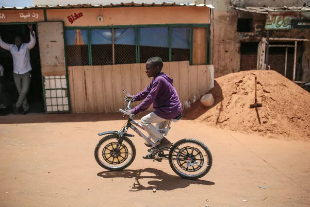 In this picture taken on Tuesday, April 14, 2015, a Sudanese boy rides a bicycle in Izba, an impoverished neighborhood on the outskirts of Khartoum, Sudan. Izba is one sign of how the constant internal wars, under Sudan's President Omar al-Bashir, have shaped, Khartoum. Before al-Bashir came to power, Izba was home to a community of Arab tribesmen who had settled here to be close to the capital. (Photo by Mosa'ab Elshamy/AP Photo)