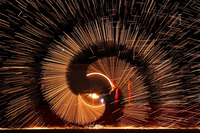 Folk artists throw molten iron to create sparks during an event to celebrate the Chinese Lunar New Year, in Shangqiu, Henan province, China February 11, 2019. (Photo by Reuters/China Stringer Network)