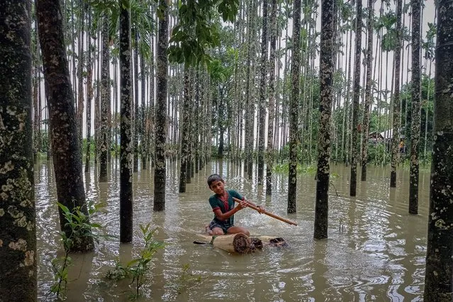 A child wades through a flooded area using a makeshift raft at Maulovir Para, Cox's Bazar on July 30, 2021 after monsoon floods and landslides have cut off more than 300,000 people in villages across southeast Bangladesh and killed at least 20 people including six Rohingya refugees. (Photo by Tanbir Miraj/AFP Photo)