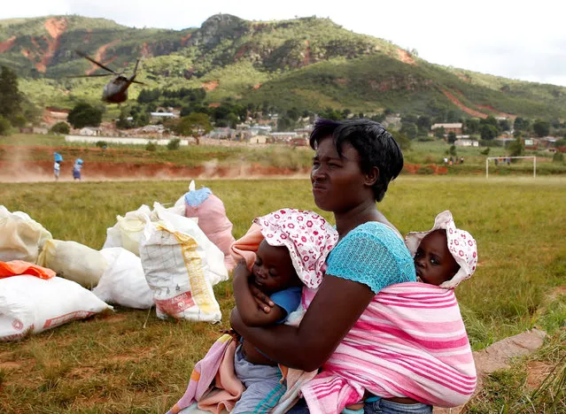A woman carrying children looks away as a helicopter throws up dust as it takes off after delivering food aid at Ngangu in Chimanimani, Zimbabwe, March 22, 2019. (Photo by Philimon Bulawayo/Reuters)