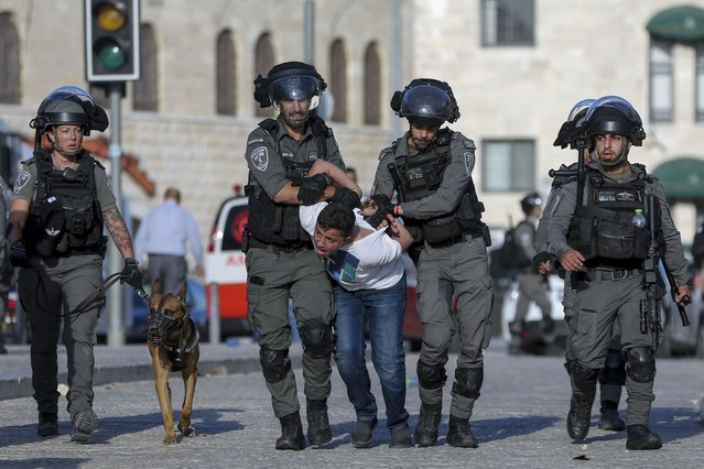 Israeli border police officers detain a Palestinian youth during clashes between Palestinians and Israeli police as thousands of Muslims flocked to Jerusalem's Old City to celebrate the Muslim Prophet Muhammad's birthday, Tuesday, October 19, 2021. (Photo by Mahmoud Illean/AP Photo)