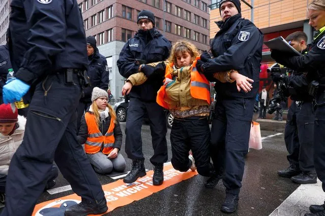 Police officers detain an activist of the “Letzte Generation” (Last Generation) as they carry her off a road, during a protest for a speed limit on highways as well as for affordable public transport, in Berlin, Germany on December 5, 2022. (Photo by Christian Mang/Reuters)