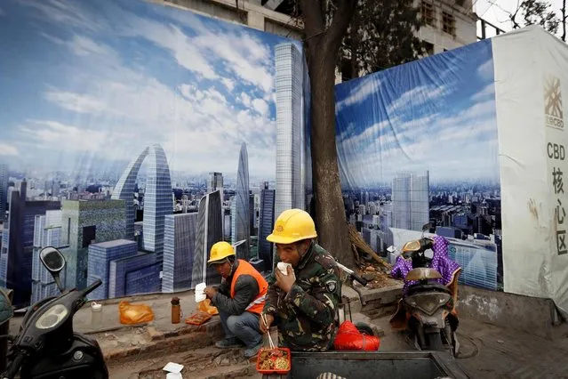 In this December 13, 2016 photo, workers eat their lunch outside a construction site wall depicting the skyline of the Chinese capital at the Central Business District in Beijing. Chinese manufacturing expanded in January at close to its fastest pace in two years as heavy government spending and a bank lending boom helped to keep economic activity steady headed into 2017, a survey showed Wednesday, February 1, 2017. (Photo by Andy Wong/AP Photo)