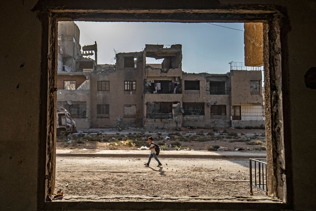 A Syrian student walks to school past damaged buildings in the northern city of Raqqa, on September 23, 2021. (Photo by Delil Souleiman/AFP Photo)