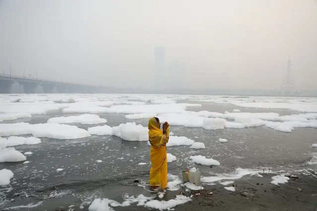 A woman prays on the banks of the river Yamuna on a smoggy morning in New Delhi, November 8, 2021. (Photo by Anushree Fadnavis/Reuters)