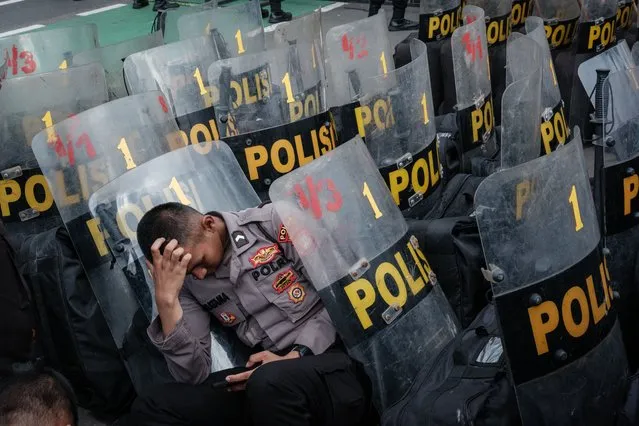 A policeman rests among the shields during a demonstration demanding the impeachment of Indonesia's President Joko Widodo, the rejection of the general election results and the removal of members of the General Election Commission (KPU) at the entrance of the parliament in Jakarta on March 5, 2024. (Photo by Yasuyoshi Chiba/AFP Photo)