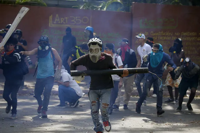 Anti-government protesters, one carrying a homemade mortar, take cover as security forces fire tear gas to disperse demonstrators in Caracas, Venezuela, Wednesday, May 1, 2019. (Photo by Fernando Llano/AP Photo)