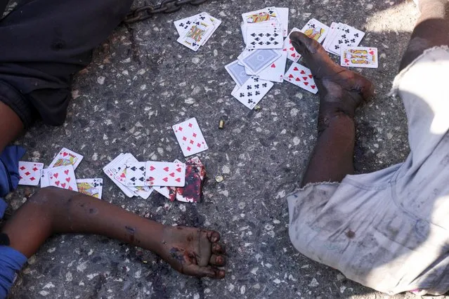 Blood-stained playing cards lie on the ground next to the bodies of two men who were shot dead, in Port-au-Prince, Haiti, on March 18, 2024. (Photo by Ralph Tedy Erol/Reuters)