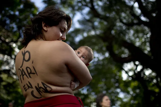 Eugenia Gimenez, holding her baby Nicanor, stands with her back covered with the words in Spanish: “I gave birth at home” during a protest against restrictions on home births in Buenos Aires, Argentina, Thursday, May 14, 2015. (Photo by Natacha Pisarenko/AP Photo)