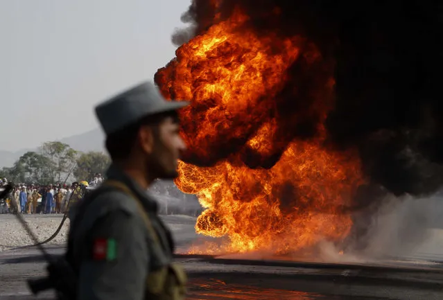 Afghan policeman stands by a burning oil tanker after an explosive device which was planted underneath it exploded, on the Jalalabad-Torkham highway, east of Kabul, Afghanistan, Wednesday, October 20, 2010. (Photo by Rahmat Gul/AP Photo)