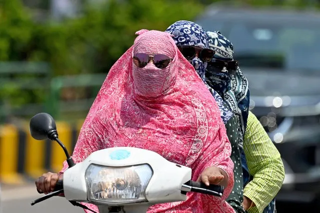 Women cover their faces with a cloth while riding a two-wheeler on a hot day, in Raipur on April 15, 2024. (Photo by Idrees Mohammed/AFP Photo)