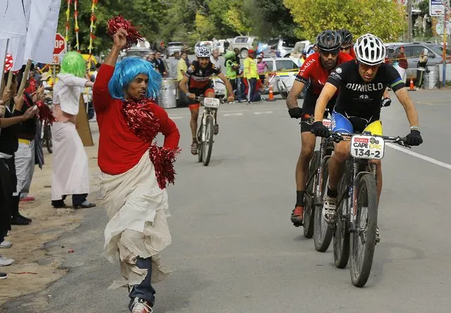 Riders pedal past a cross dresser during stage 4 of the annual ABSA Cape Epic mountain bike stage race, Greyton, South Africa, 27 March 2014. (Photo by Kim Ludbrook/EPA)