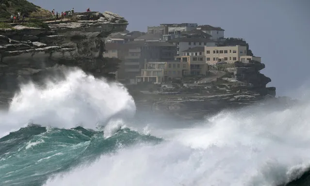 People watch the spray as large seas pound the coast near Tamarama Beach in Sydney on March 6, 2017. (Photo by William West/AFP Photo)