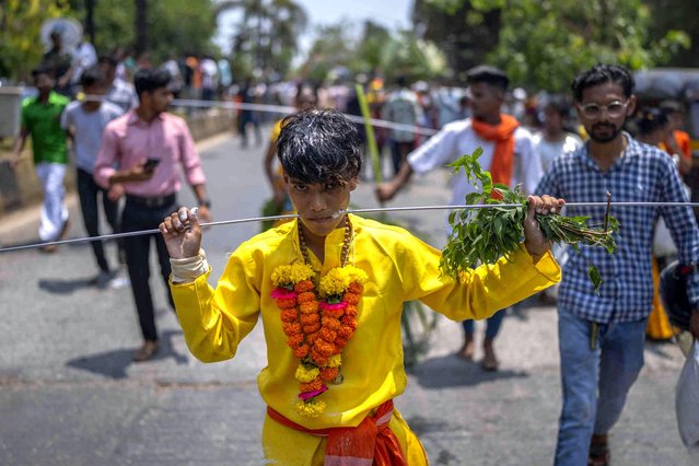 An Indian Tamil Hindu devotee, cheeks pierced with a metal spear, participates in a religious procession marking “Panguni Uthiram” festival in Mumbai, India, Tuesday, April 23, 2024. Devotees perform acts of self- affliction to seek blessings of Hindu god Murugan. (Photo by Rafiq Maqbool/AP Photo)