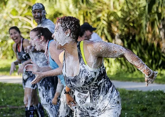 Participants race after sliding down the soapy slip-and-slide in the Rugged Runner Challenge in West Palm Beach, on April 6, 2014. (Photo by Damon Higgins/The Palm Beach Post)
